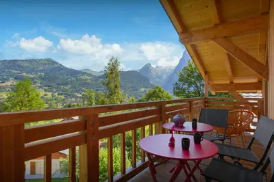 a porch with two tables and chairs and mountains at MontCriou - OVO Network in Samoëns
