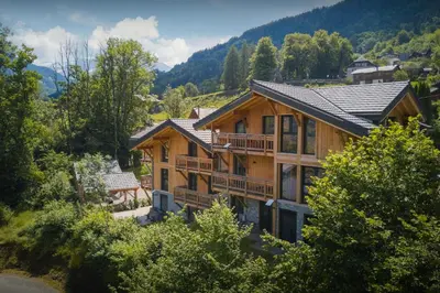 an image of a log house with mountains in the background at MontCriou - OVO Network in Samoëns
