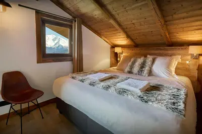 a bedroom with a bed with a window and a chair at Chalet Vardache - OVO Network in Cordon