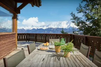 a table on a deck with a view of mountains at Chalet Vardache - OVO Network in Cordon