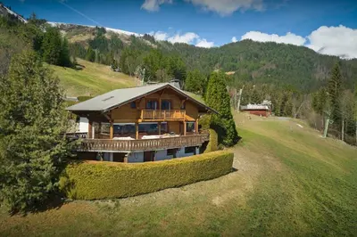 a large wooden house on a hill in a field at Chalet Vardache - OVO Network in Cordon