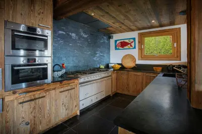 a kitchen with wooden cabinets and a stove top oven at Chalet Vardache - OVO Network in Cordon