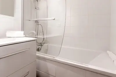 a white bathroom with a shower and a sink at Appt Donna - Chamonix Centre in Chamonix-Mont-Blanc