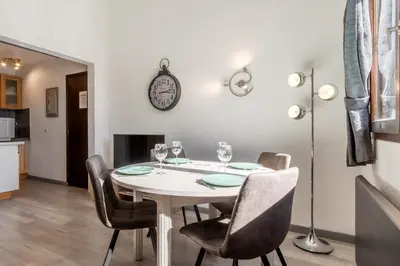 a dining room with a table with chairs and a clock on the wall at Appt Donna - Chamonix Centre in Chamonix-Mont-Blanc