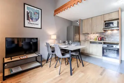 a kitchen with a table and chairs and a television at Triplex - Hypercentre - Balcon avec vue montagnes in Chamonix-Mont-Blanc
