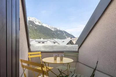 a small table and chairs on a balcony with a mountain at Triplex - Hypercentre - Balcon avec vue montagnes in Chamonix-Mont-Blanc
