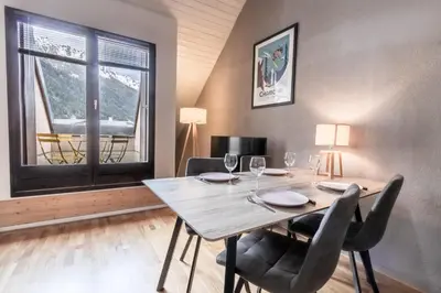 a dining room with a table and chairs and a window at Triplex - Hypercentre - Balcon avec vue montagnes in Chamonix-Mont-Blanc