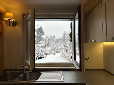 a kitchen window with a view of a snowy yard at Alpine Escape Mont Blanc at Your Window in Chamonix-Mont-Blanc