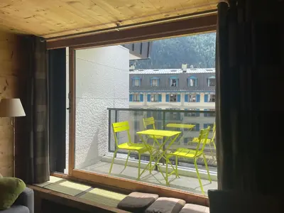a view of a balcony with yellow chairs and a table at Magnifique Studio Plein centre vue panoramique in Chamonix-Mont-Blanc