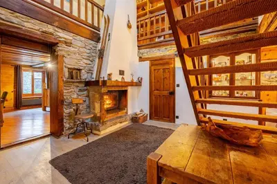 a living room with a stone fireplace and a table at Marmotte Mountain Manor in Chamonix-Mont-Blanc