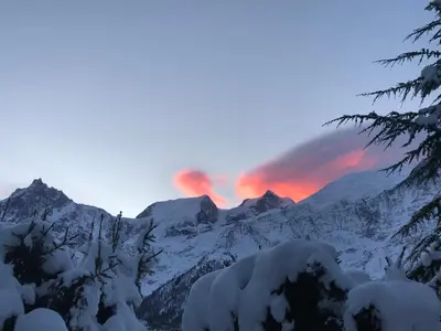 a sunset over a snowy mountain range with a rainbow at Résidence plein sud en vallée de Chamonix in Les Houches