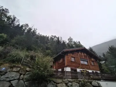 a wooden house on a hill with a mountain at Résidence plein sud en vallée de Chamonix in Les Houches