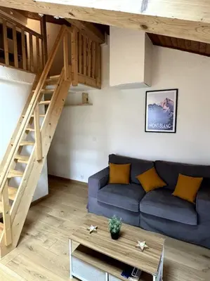 a living room with a blue couch and a wooden stairs at Le Cozet in Saint-Gervais-les-Bains