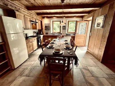 a kitchen with a long table with chairs and a refrigerator at La ferme de la Tour - Vallée de Chamonix in Servoz
