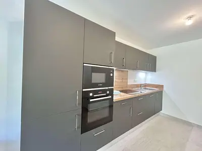 a kitchen with stainless steel appliances and gray cabinets at Appartement Neuf 3 Pièces avec Terrasse et Jardin, Proche Remontées Mécaniques, Parking Inclus - FR-1-597-179 in Combloux