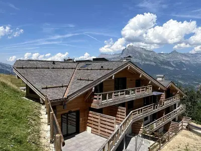 a log cabin with mountains in the background at Appartement Neuf 3 Pièces avec Terrasse et Jardin, Proche Remontées Mécaniques, Parking Inclus - FR-1-597-179 in Combloux