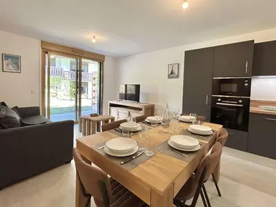 a kitchen and dining room with a table and chairs at Appartement Neuf 3 Pièces avec Terrasse et Jardin, Proche Remontées Mécaniques, Parking Inclus - FR-1-597-179 in Combloux