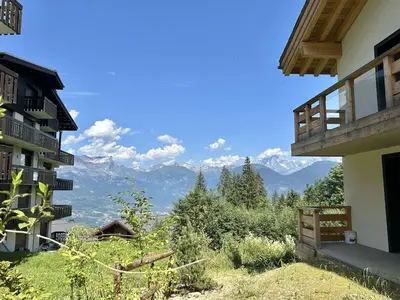 a view of the mountains from a building at Appartement Neuf 3 Pièces avec Terrasse et Jardin, Proche Remontées Mécaniques, Parking Inclus - FR-1-597-179 in Combloux