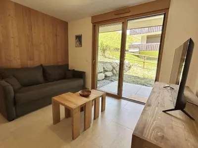 a living room with a couch and a table at Appartement Neuf 3 Pièces avec Terrasse et Jardin, Proche Remontées Mécaniques, Parking Inclus - FR-1-597-179 in Combloux