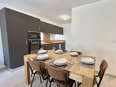 a dining room with a wooden table and chairs at Appartement Neuf 3 Pièces avec Terrasse et Jardin, Proche Remontées Mécaniques, Parking Inclus - FR-1-597-179 in Combloux