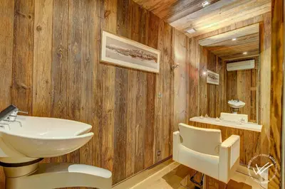 a bathroom with wooden walls and a sink and mirror at Mirage in Demi-Quartier