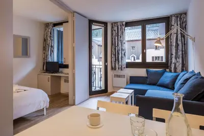 a bedroom with a large white bed and a dining room at Slalom Residence Chamois Blanc in Chamonix-Mont-Blanc