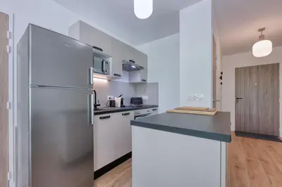 a kitchen with a stainless steel refrigerator and white cabinets at Alpina 108 départ ski & rando depuis le Bettex in Saint-Gervais-les-Bains