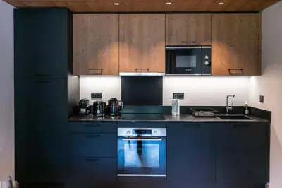 a kitchen with black cabinets and a stove and a microwave at L'Eclat des Veriaz - Megève Appartement 2 chambres, Résidence de standing in Megève