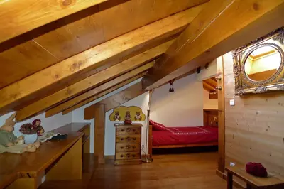 a small attic bedroom with wooden ceilings and a red bed at Location de charme 4 étoiles à Passy in Passy