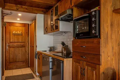 a kitchen with wooden cabinets and a sink and a microwave at Balcon de l'Arve - Charming Duplex in Chamonix Centre in Chamonix-Mont-Blanc