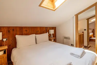 a bedroom with a white bed with a wooden headboard at Balcon de l'Arve - Charming Duplex in Chamonix Centre in Chamonix-Mont-Blanc