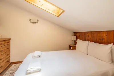 a bedroom with a white bed with a wooden headboard at Balcon de l'Arve - Charming Duplex in Chamonix Centre in Chamonix-Mont-Blanc