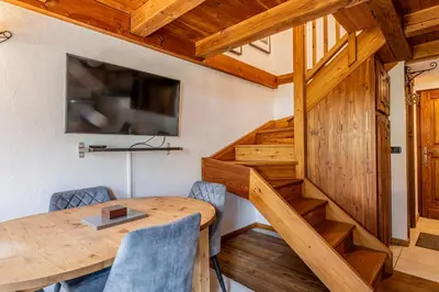 a dining room with a wooden table and a staircase at Balcon de l'Arve - Charming Duplex in Chamonix Centre in Chamonix-Mont-Blanc
