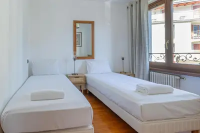 two beds in a white room with a window at Coeur des Alpes - A spacious 3-bedroom apartment with spectacular views in Chamonix-Mont-Blanc