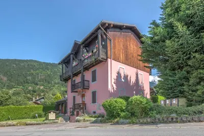 a pink house with a wooden roof at Duplex de Miage - Welkeys in Saint-Gervais-les-Bains