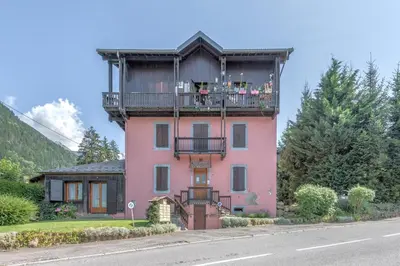a pink house with a balcony on the side of a road at Duplex de Miage - Welkeys in Saint-Gervais-les-Bains