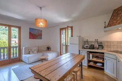 a kitchen and living room with a wooden table at Duplex de Miage - Welkeys in Saint-Gervais-les-Bains