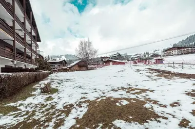 a snow covered street next to a building at Appartement l'Olympique - Ski in & ski out in Megève