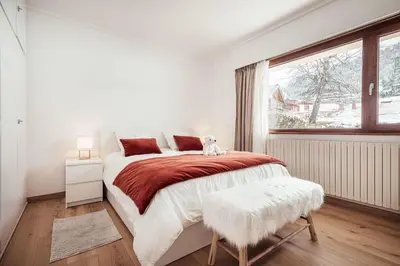 a white bedroom with a large bed and a window at Appartement l'Olympique - Ski in & ski out in Megève