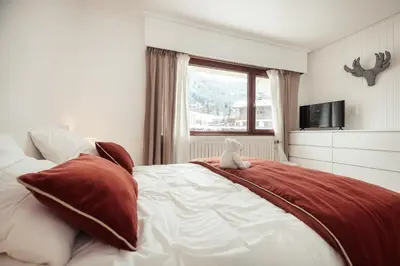 a teddy bear sitting on a bed in a bedroom at Appartement l'Olympique - Ski in & ski out in Megève