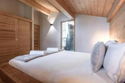a bedroom with a large white bed with wooden walls at Les Trabets - Bellevue telecabine - Renove in Les Houches