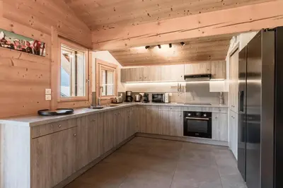 a kitchen with wooden cabinets and a stainless steel refrigerator at Les Trabets - Bellevue telecabine - Renove in Les Houches