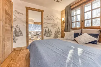 a bedroom with a large bed with a blue blanket at Apt 8 pers hyper centre à Chamonix in Chamonix-Mont-Blanc