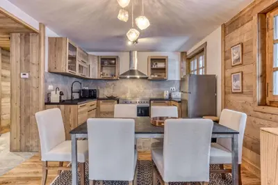 a kitchen with a table and chairs and a refrigerator at Apt 8 pers hyper centre à Chamonix in Chamonix-Mont-Blanc