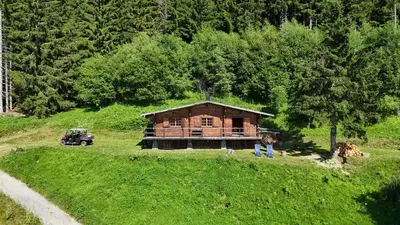 a house on top of a grassy hill next to a forest at Chalet d'alpage avec vue incroyable in Saint-Gervais-les-Bains