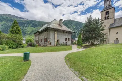 an old building with a clock tower on a grass field at Apartment Picasso in Chamonix-Mont-Blanc