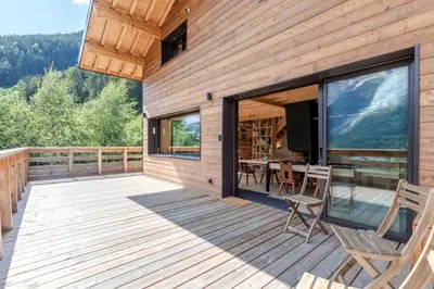 a wooden deck with a table and chairs on it at Chalet Soljanel in Chamonix-Mont-Blanc