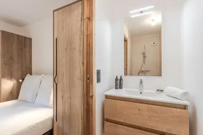 a bathroom with a sink and a bed and a mirror at Alpage Mont Blanc in Combloux
