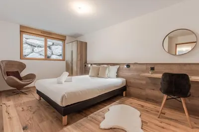 a bedroom with a bed and a mirror and a chair at Alpage Mont Blanc in Combloux