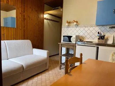 a living room with a couch and a kitchen at Studio meublé bon emplacement in Chamonix-Mont-Blanc